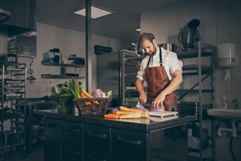 Kock skär grönsaker i köket